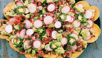 Homemade fully loaded black bean nachos with green and red salsas